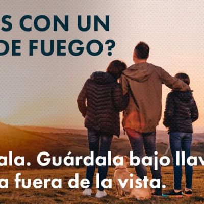 Una familia de tres miembros con un perro cerca de un maletero abierto al atardecer. Un texto en español aconseja a los viajeros que lleven un arma de fuego que la descarguen, la cierren con llave y la mantengan fuera de la vista. Aparece el logotipo de Colorado Hablemos de Armas.