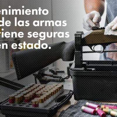 Una persona limpia un rifle sobre una mesa con artículos de limpieza para armas, munición y un estuche para armas. El texto en español dice, El mantenimiento regular de las armas las mantiene seguras y en buen estado.