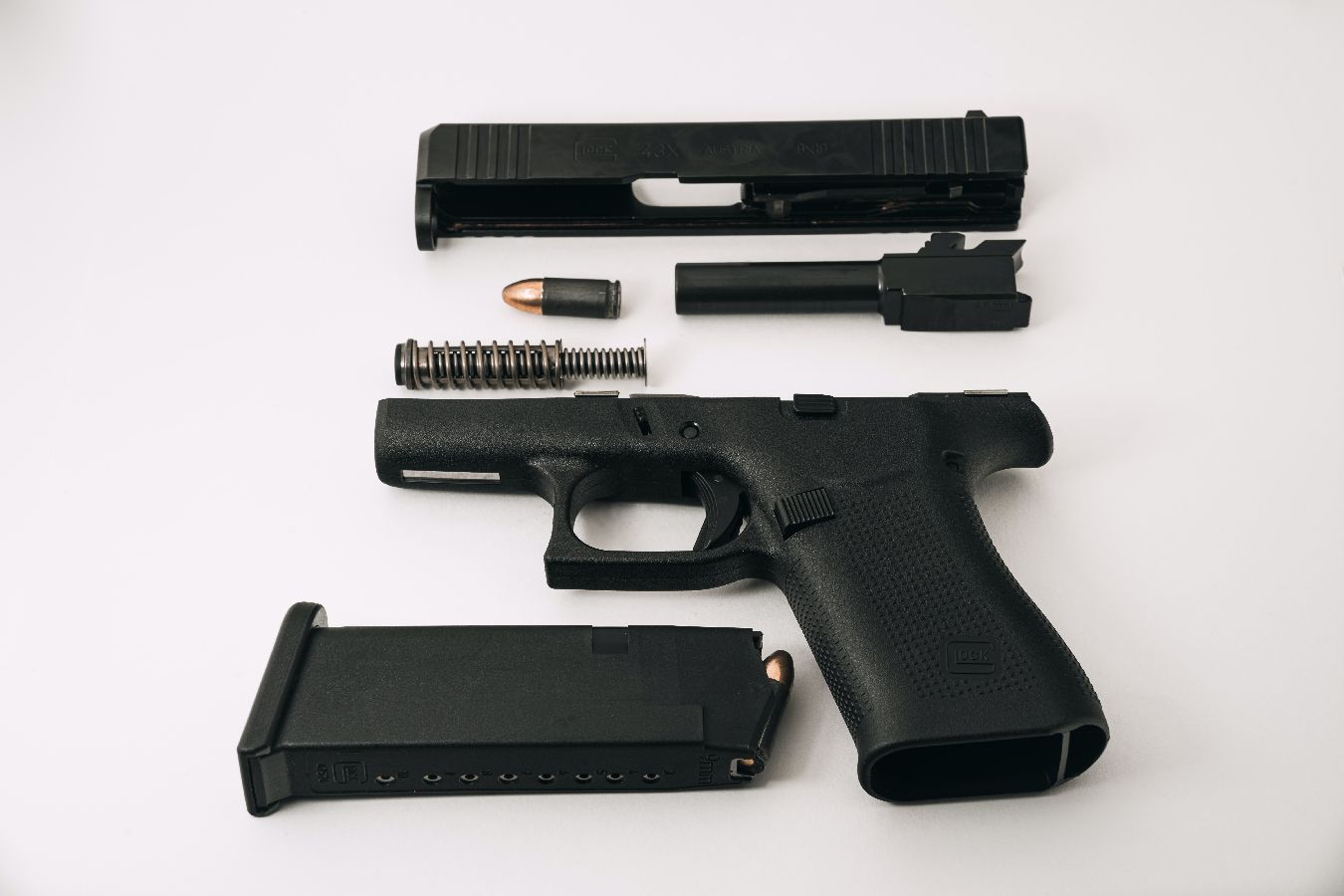 A black handgun with a magazine and other parts on a white background.
