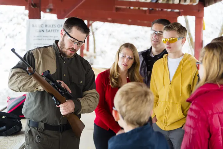 A group of people looking at a rifle.