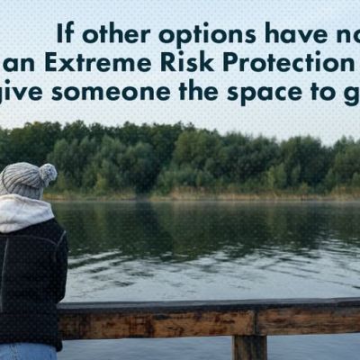 A person in a winter hat and jacket stands at a wooden railing overlooking a lake. Text reads: If other options have not worked, an Extreme Risk Protection Order can give someone the space to get support.