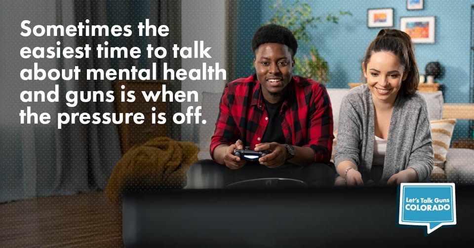 Two people smile while playing video games on a couch, with text about talking about mental health and guns.