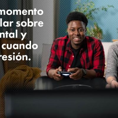Un hombre y una mujer jóvenes sentados en un sofá sonríen y juegan a videojuegos. El texto en español dice, El mejor momento para hablar sobre salud mental y armas es cuando no hay presión. En la esquina inferior derecha aparece el logotipo de Lets Talk Guns Colorado.