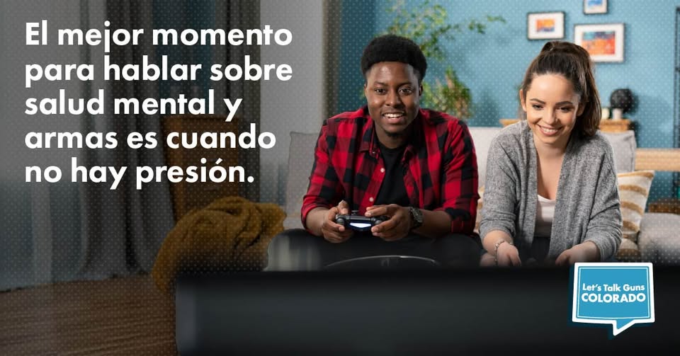Un hombre y una mujer jóvenes sentados en un sofá sonríen y juegan a videojuegos. El texto en español dice, El mejor momento para hablar sobre salud mental y armas es cuando no hay presión. En la esquina inferior derecha aparece el logotipo de Lets Talk Guns Colorado.